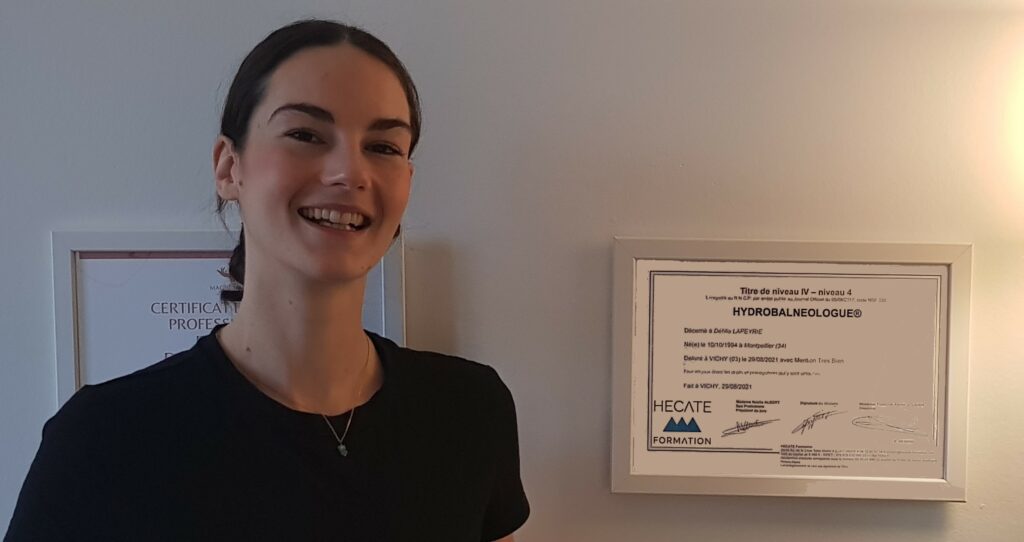  Déhlia Lapeyrie ancienne stagiaire HECATE Formation qui sourit devant son diplôme d'Hydrobalnéogue